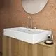 Waschtisch mit rechteckiger, weißer Keramikschüssel auf Holzunterbau. Ideal Standard Armatur in Chrom, zwei Hebel und runder Spiegel an korkgefüllter Wand.